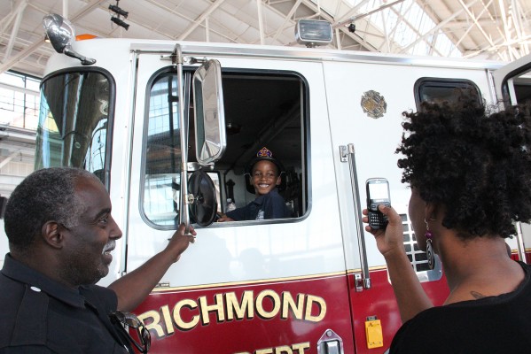 One of the most popular attractions was the big red Richmond Fire Engine parked in the pavilion. Rod Woods, Richmond Fire Fighter, spent hours helping kids in and out of the truck. Jawanda DK Moore was so excited play fireman he pretended to drive off right after this picture was taken. (Photo by: Jennifer Baires)