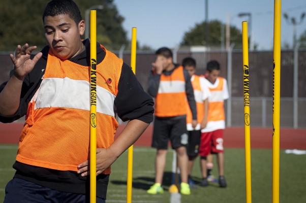 Danial Arandia Diaz, 14, maneuvers through yellow poles during a running exercise Monday morning at Kennedy High. The first-time player said practice has taught him to control his feet. (Photo by: Tyler Orsburn)