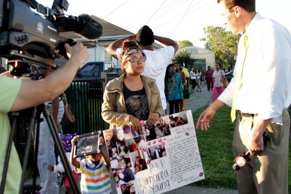 Dimarea Young's girlfriend holds a poster tribute she made for him. A little boy holds up a photo of the two together. TV crews were eager to interview mourners. Photo by: Anne Hoffman.