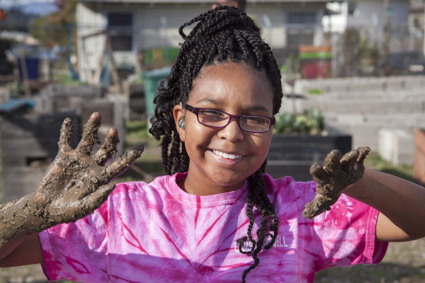 Georgie Fields shows off her mud-clad hands after mixing the adobe clay. (Photo by Brittany Murphy)